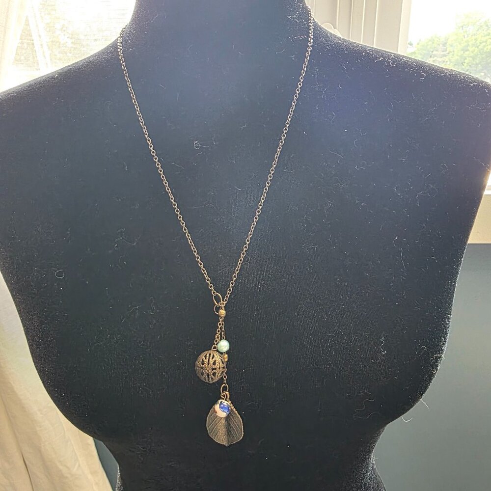 Long dark gold necklace with leaf and filigree bead